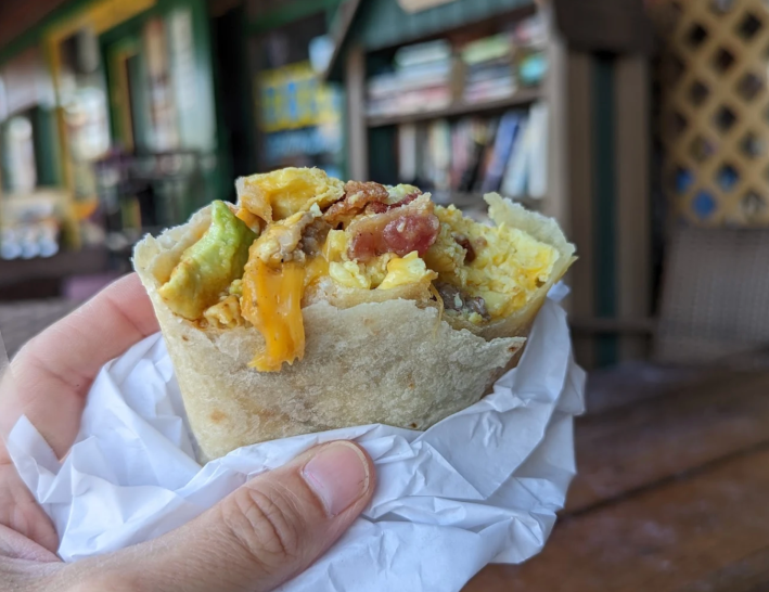 Cheesy breakfast burrito being held up.